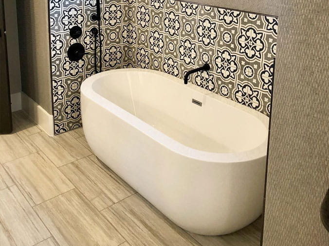 White free standing bath tub with tile back wall