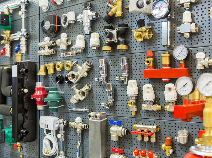 Brass plumbing fittings on a pegboard in a plumbing supply store